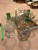 Overall group of various clear and green glass vases in different sizes and shapes.