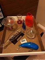 Photo showing full assortment of eight glass decor items including Mayflower ship sculpture, glass dolphin, orange vase, and other glass pieces arranged in a cardboard box.