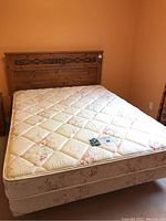 Full view of assembled queen bed showing wooden headboard, mattress, box spring on metal frame