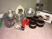 Photo of bowls, lids, measuring cups, colander, salt and pepper shakers on floor