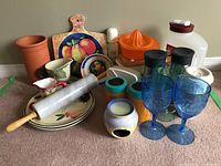 Full view of kitchen lot showing terra cotta wine chiller, rolling pin, plates, creamers, glasses, and citrus juicer