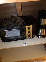 Kenmore black toaster oven/broiler with yellow control panel and assorted parts inside on shelf.