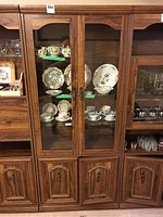 Front view of the closed wall unit showing wood finish, glass doors and lower cabinets.