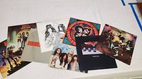 Seven classic rock vinyl LP records laid out showing album cover art including Kiss and Aerosmith albums