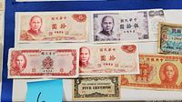 Photo showing multiple Chinese bank notes mostly 10 and 50 Yuan denominations plus one Japanese Five Centavos note laid out horizontally