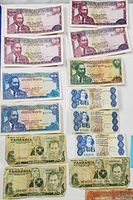 Photo showing various African banknotes including Tanzanian Shillings, Kenyan Shillings, South African Rand from the 1970s in mixed condition.