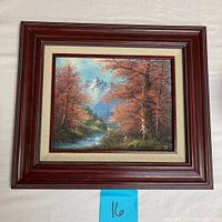 Framed oil painting showing autumnal landscape with a flowing stream and snow-capped mountains in background.