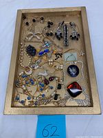 Assorted costume jewelry including earrings, pendants, necklaces in a wooden tray