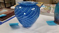 Full side view of the blue glass vase showing its rounded shape and swirling blue pattern.