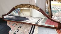Front view of vintage beveled glass mirror with wooden arched frame and gold ornamental detail at arch center.