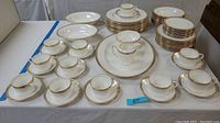 Full overview of cups, saucers, plates, serving bowls, platter, and creamer on table