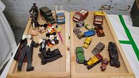 Overview of entire toy collection laid out on two wooden trays showing character figurines and miniature vehicles.