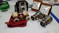 Full lot view including two pairs of opera glasses, Brownie Starlet box camera, and two Westclox travel clocks.