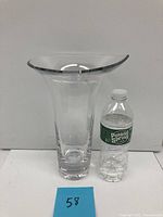 Full view of the crystal vase next to a water bottle for scale, showing its tulip shape and wide flared rim.
