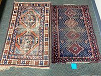 Two rugs side by side on carpeted floor showing full lot with light and dark rugs