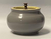 Stoneware tobacco jar with light grey glaze, viewed from front showing brass fitted top with screw mechanism.