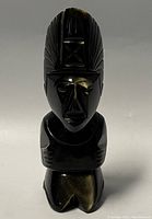 Front view showing facial features, crossed arms and full height of sculpture.
