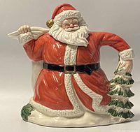 Front view of the Fitz & Floyd Santa Claus teapot showing Santa holding a Christmas tree and wearing a red suit with white trim.