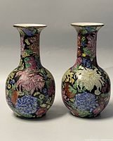 Front view of two ceramic vases side by side showing detailed floral designs on black backgrounds.