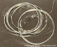 Four silver baguette-style bangles and cuffs arranged flat on a reflective surface. Shows overall condition and type of bracelets.