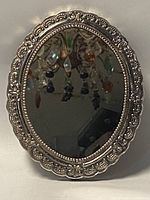 Front view of oval mirror showing ornate decorative 925 silver frame and reflective surface.