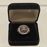 Lion head ring displayed in black velvet box showing top lion head design.