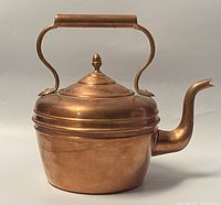Side view of the antique copper kettle showing body, curved spout and handle with rectangular grip, and lid finial.