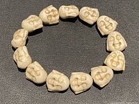 Full view of the stretchy bracelet showing all carved jade Buddha head beads arranged in a circle on a dark surface.