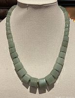 Front view of a 20-inch necklace made of light green jade beads in square and cylindrical shapes, showing the arrangement and size of the beads.
