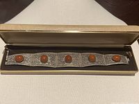 Bracelet displayed inside its vintage box showing decorative silver and amber design.