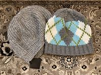 Two knit hats on carpet background, one ribbed light grey with Club Monaco tag and one gray with argyle pattern in blue, white, and green.