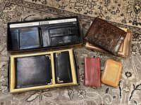 Overview of all wallets and key holders including boxed sets and individual items on a patterned rug.