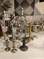 Nine assorted glass and metal candle holders arranged on a kitchen counter, showing variety of sizes, shapes, and finishes.