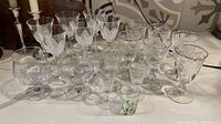 Eighteen glassware pieces including goblets, cocktail glasses, and shots on a white surface.