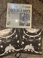 Thick as a Brick vinyl album with newspaper-style cover and two A Passion Play vinyl albums with surrealistic covers and booklets visible.