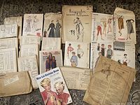Group of vintage sewing patterns and knitting books laid out on floor, showing variety of pattern covers and aged condition.