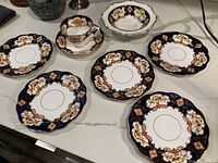 Full view of five plates, bowl, teacup, and saucer on a table showing overall lot contents and design.