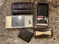 Five vintage wallets and kits arranged on a carpet including boxed wallets and a keychain in original packaging