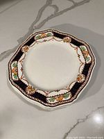 Single Royal Caledonia plate showing full patterned surface and scalloped edges on a white background.