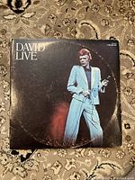 Front cover of the David Bowie 'David Live' vintage double album set showing David Bowie in white suit on stage, with wear and ring marks on cover.
