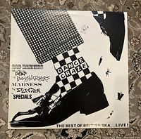 Front record sleeve with graphic black and white design showing legs in patterned pants, shoes, and band names including Bad Manners, The Beat, The Bodysnatchers, Madness, The Selecter, The Specials.