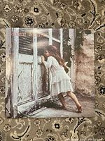 Front album cover featuring a young girl peeking through a door.