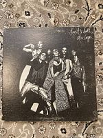 Front of 'Love It To Death' album cover showing band members in theatrical poses on black background.