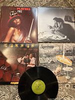 Four vinyl album covers laid out, Ohio Players 'Fire', Billy Joel 'The Stranger', Kansas '2 For The Show', and Supertramp 'Crisis? What Crisis?'. The Kansas vinyl record shown without cover.