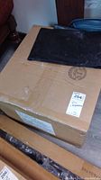 Photo of the unopened cardboard box packaging showing its size and condition with black cover on top.