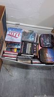 Top-down view of a bin containing a large quantity of music CDs with visible titles such as Christmas Hits and Forever Music.