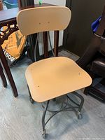 Front right-angled view showing beige resin seat and back, steel frame, and caster wheels