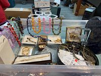 Overview of plastic bead bracelets and necklaces along with earring boxes, a Lucite decorative piece, and other costume jewelry items on display.