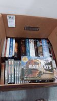 Cardboard box filled with multiple DVDs including 'Railways' DVD set visible on top.