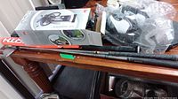 Golf shoes, golf clubs, baseball bat, air hammer on wooden table